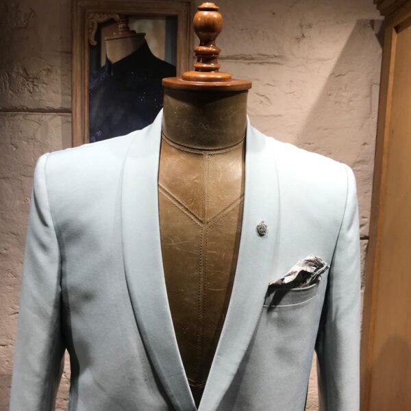 A shawl lapel powder blue blazer with single button. It is acessorised with printed  pocket square and silver crown brooch. - Image 3