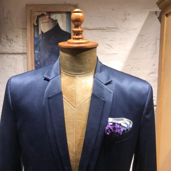 A single button blazer with dual lapel feature. It is acessorised with crumple colour effect pocket square.  A flower brooch completes the look. - Image 5