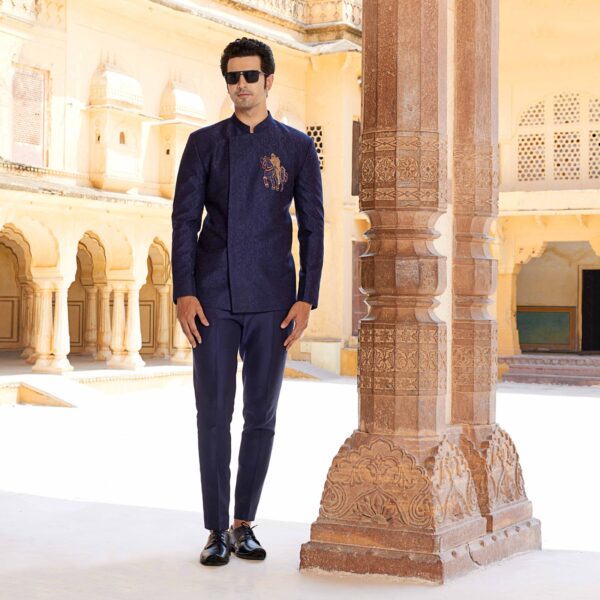 Midnight Blue Jodhpuri coat with surface detailing of Shield embroidery all over. Knight motif in antique gold on one side. Matching trousers for bottom. Styled with matching form shoes.