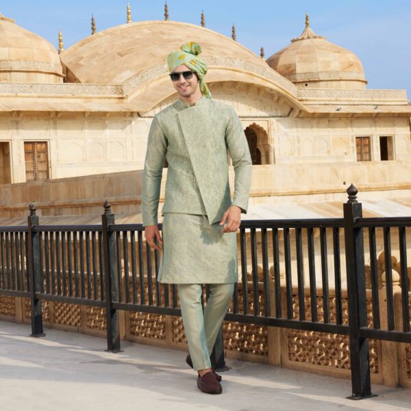 Pearl grey assymetric Jacket with surface detailing of Shield embroidery all over. Paired with knights embroidered kurta. Matching trousers for bottom. Accessorised with coordinated printed safa. Styled with brown loafers.