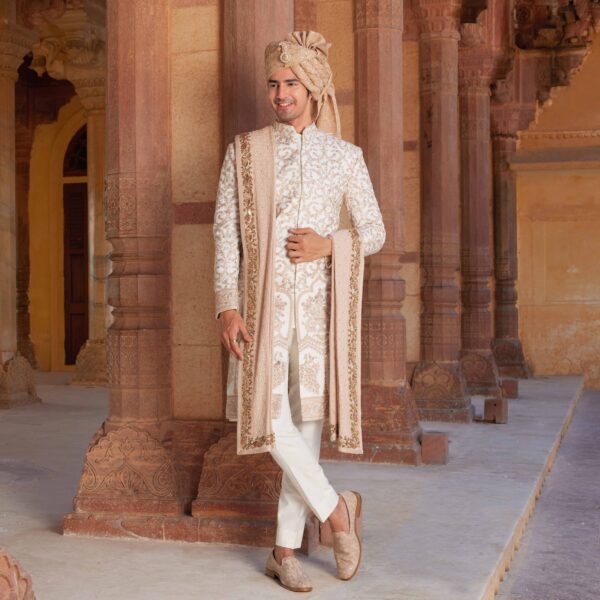 Ivory sherwani with old rose embroidery and sequence detailing all over. Matching trousers for bottom accessorised with coordinated safa and stole with peacock border. Styled with coordinated embroidered loafers.