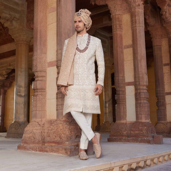 Ivory colour bandhgala with old rose embroidery & sequence detailing all over. Matching trousers for bottom. Accessorised with coordinated mala and safa. Styled with old rose embroidered loafers.