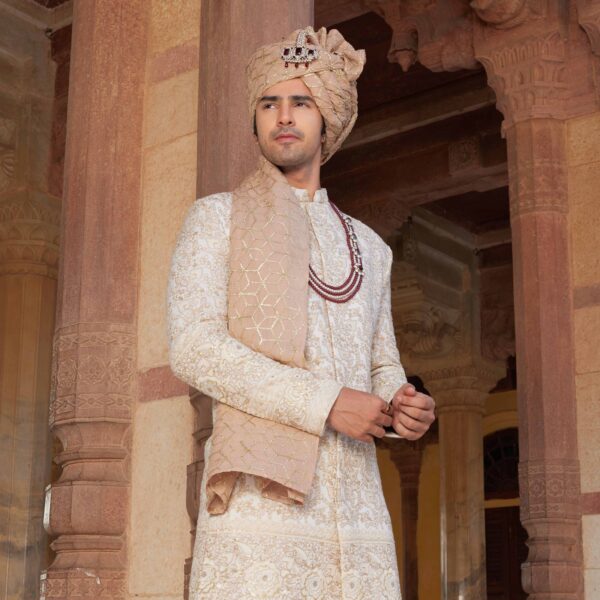 Ivory colour bandhgala with old rose embroidery & sequence detailing all over. Matching trousers for bottom. Accessorised with coordinated mala and safa. Styled with old rose embroidered loafers. - Image 2