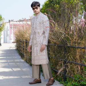 Off white Bandhgala with intricate traditional hand embroidery all over with sequins and rich border detailing in antique colour. Paired with coordinated flared copper trouser.